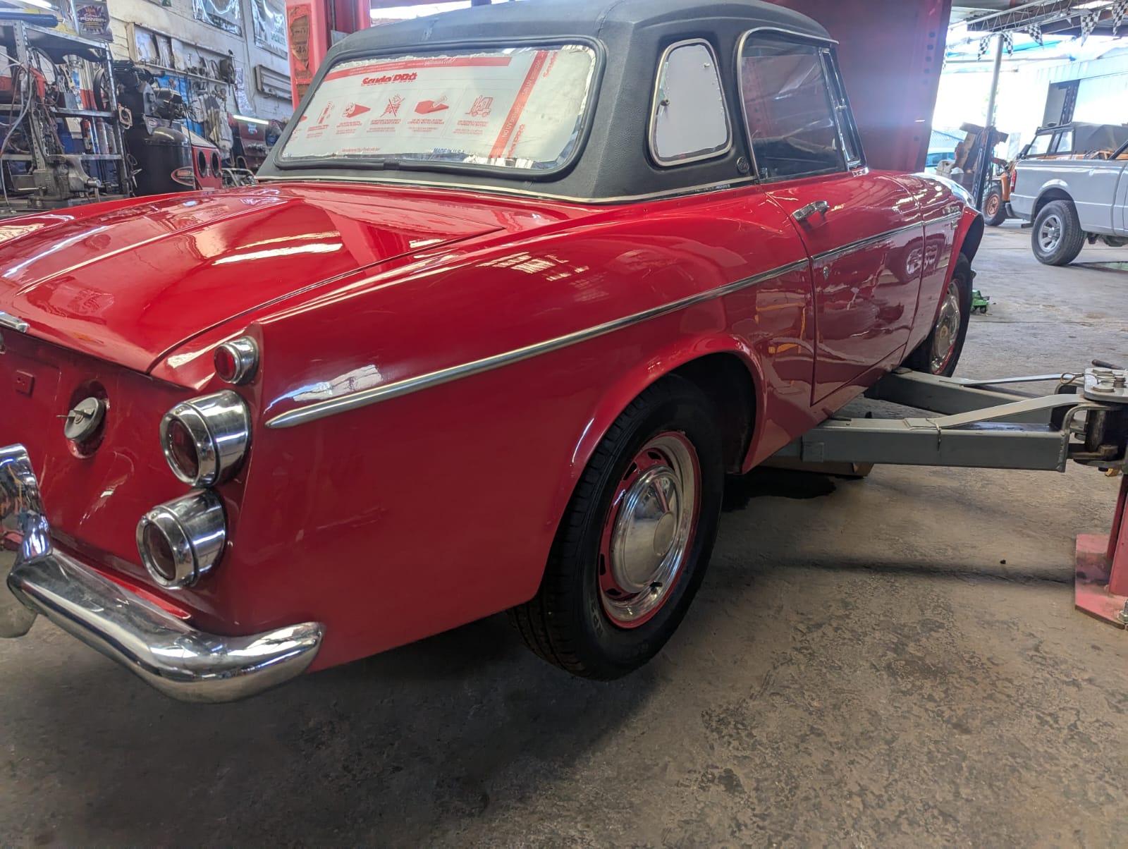 Auto clásico rojo en el elevador del taller